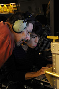 Terry Herter (left) and Ryan Lau examine fresh data gathered from the infrared telescope aboard SOFIA, a modified Boeing 747 jetliner.